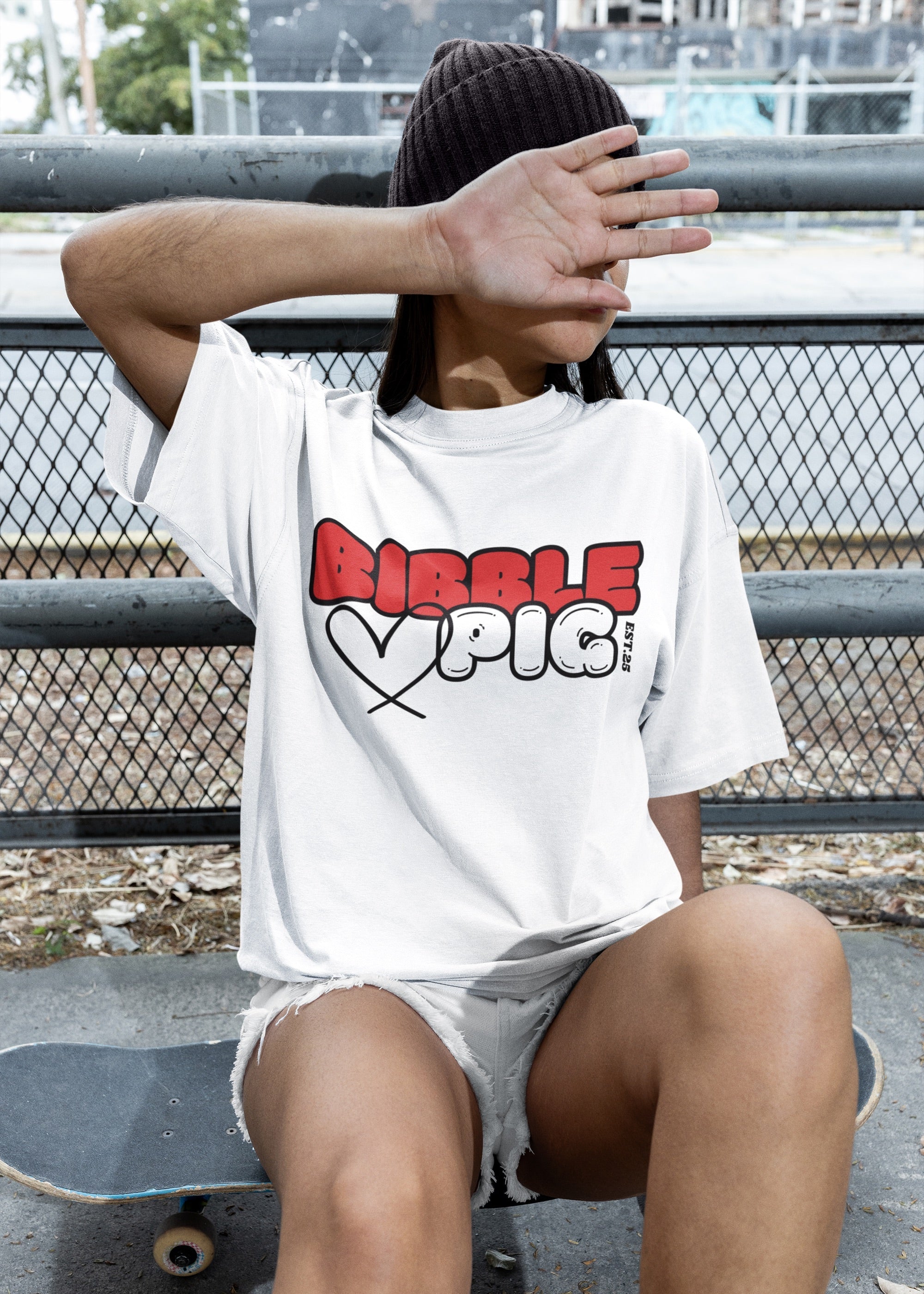 Model wearing a white oversized organic t-shirt with large Cherry Red and White Bold Logo and cute heart design.
