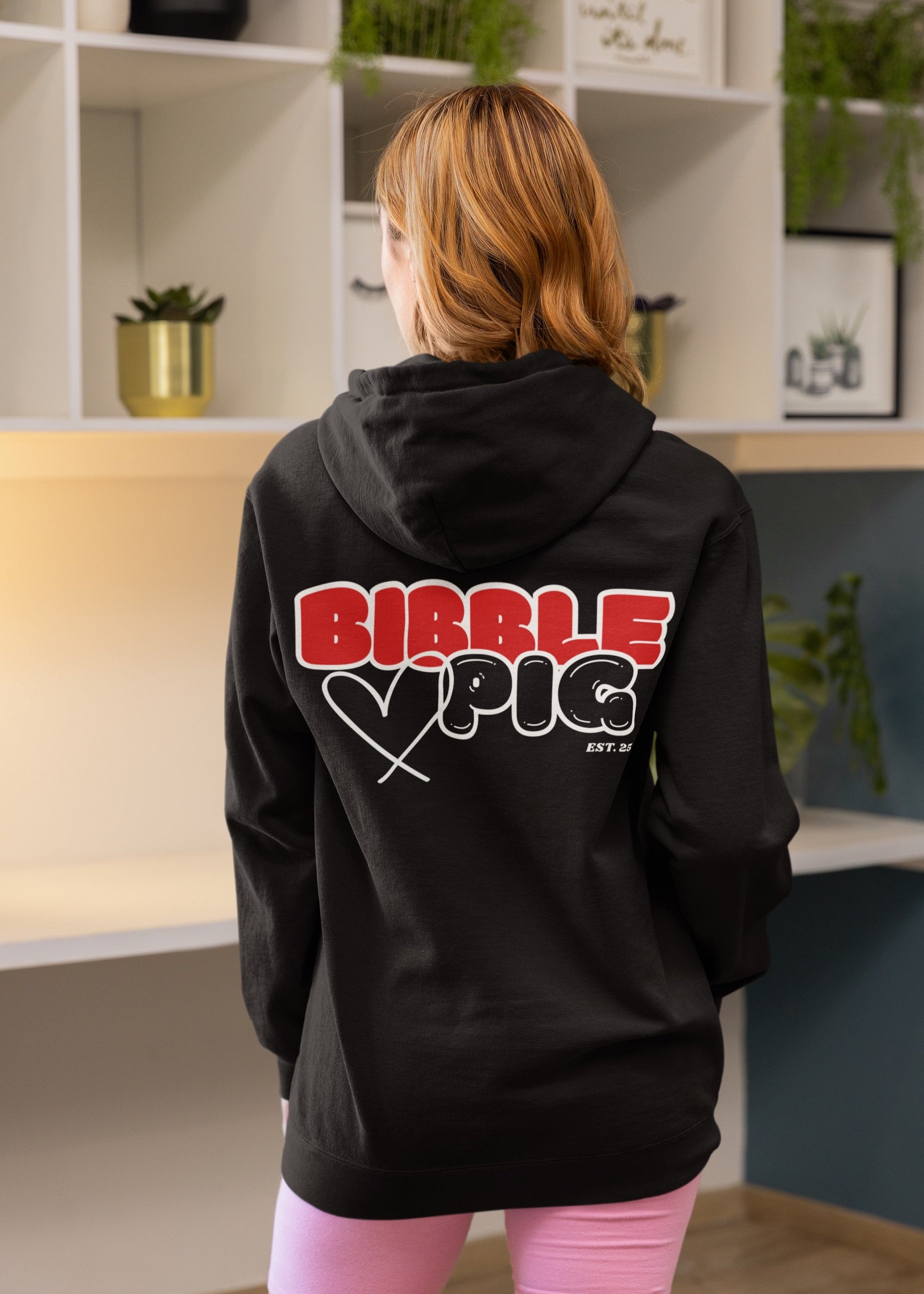 Model wearing black oversized hoodie with large bold Bibble Pig graphic on the back.