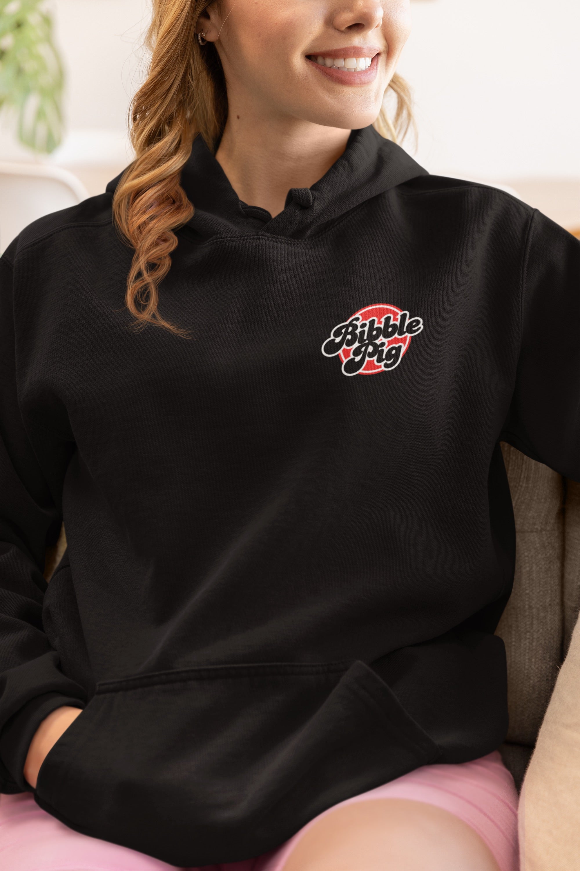 Model wearing black oversized hoodie with bold red Bibble Pig front logo.