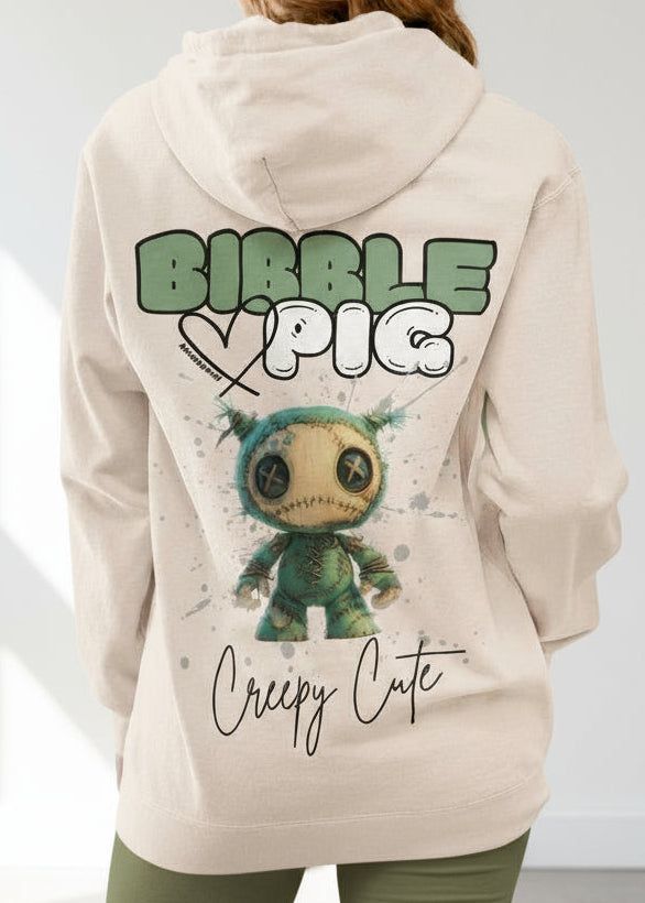 Close up of a model wearing a cream organic hoodie featuring goth style creepy cute Night Terror Voodoo style graphic. 