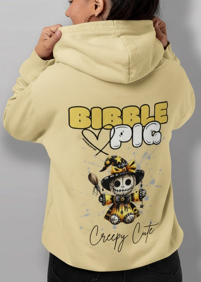 Close up view of model wearing a yellow oversized organic hoodie with our Bibble Pig Signature Bold Logo and Creepy Cute Soul Creeper Doll Graphic.