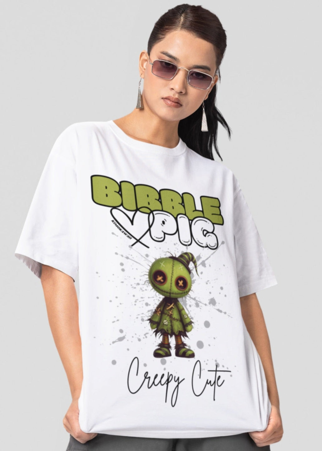 Close up of a model wearing white oversized t-shirt featuring Tattered Stitches Voodoo doll graphic and bold Bibble Pig Logo. 