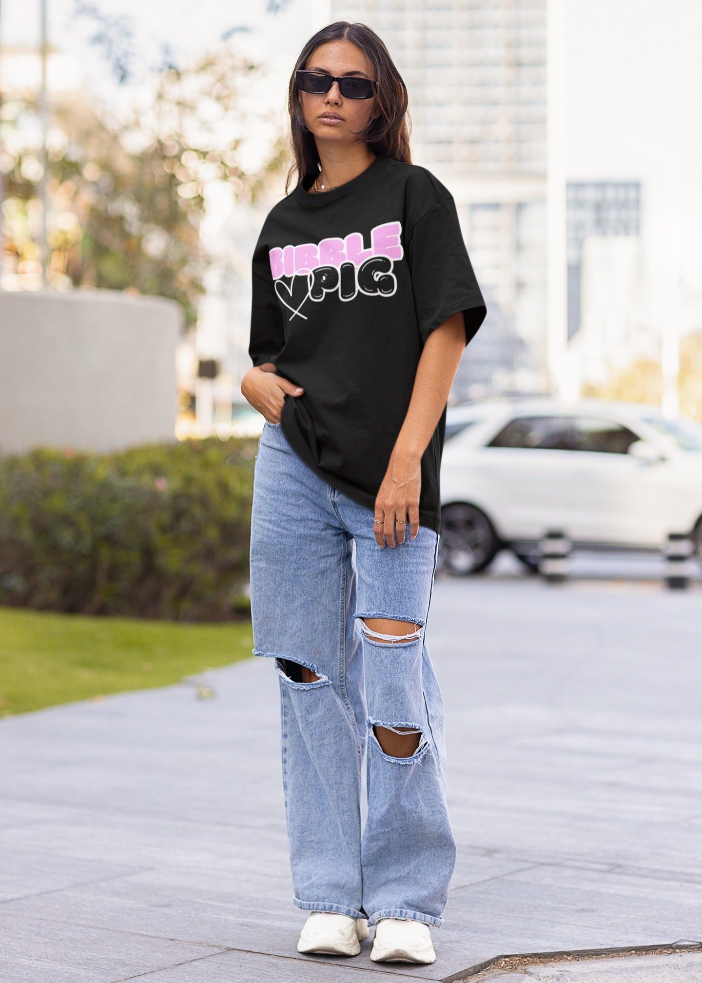Model wearing Bibble Pig oversized organic cotton t shirt with bubblegum pink logo and black heart design. Unisex UK streetwear fashion.