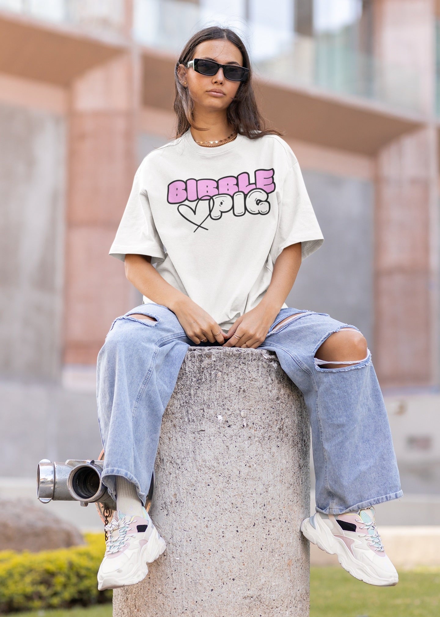 Model wearing Bibble Pig oversized organic cotton t shirt with bubblegum pink logo and black heart design. Unisex UK streetwear fashion.
