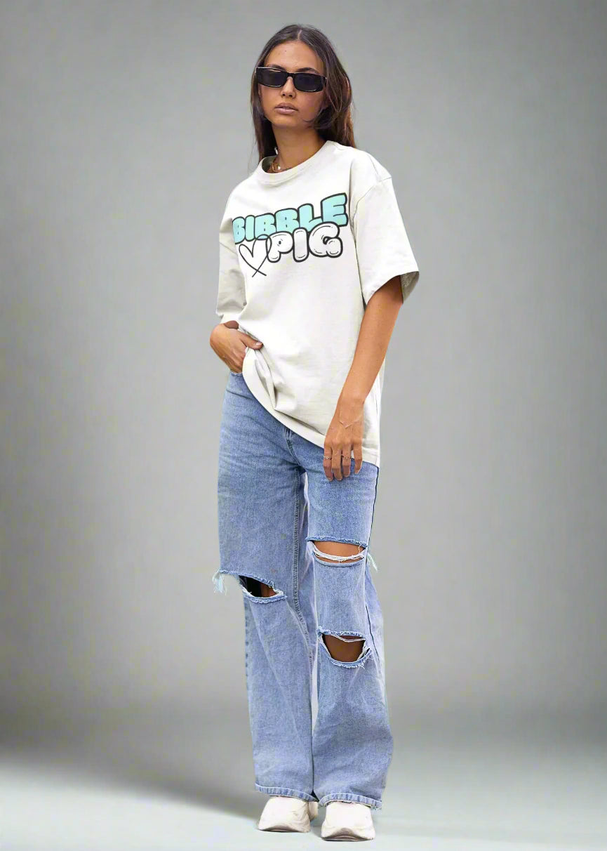 Model wearing Bibble Pig oversized organic cotton t shirt with pastel blue logo and black heart design. Unisex UK streetwear fashion.
