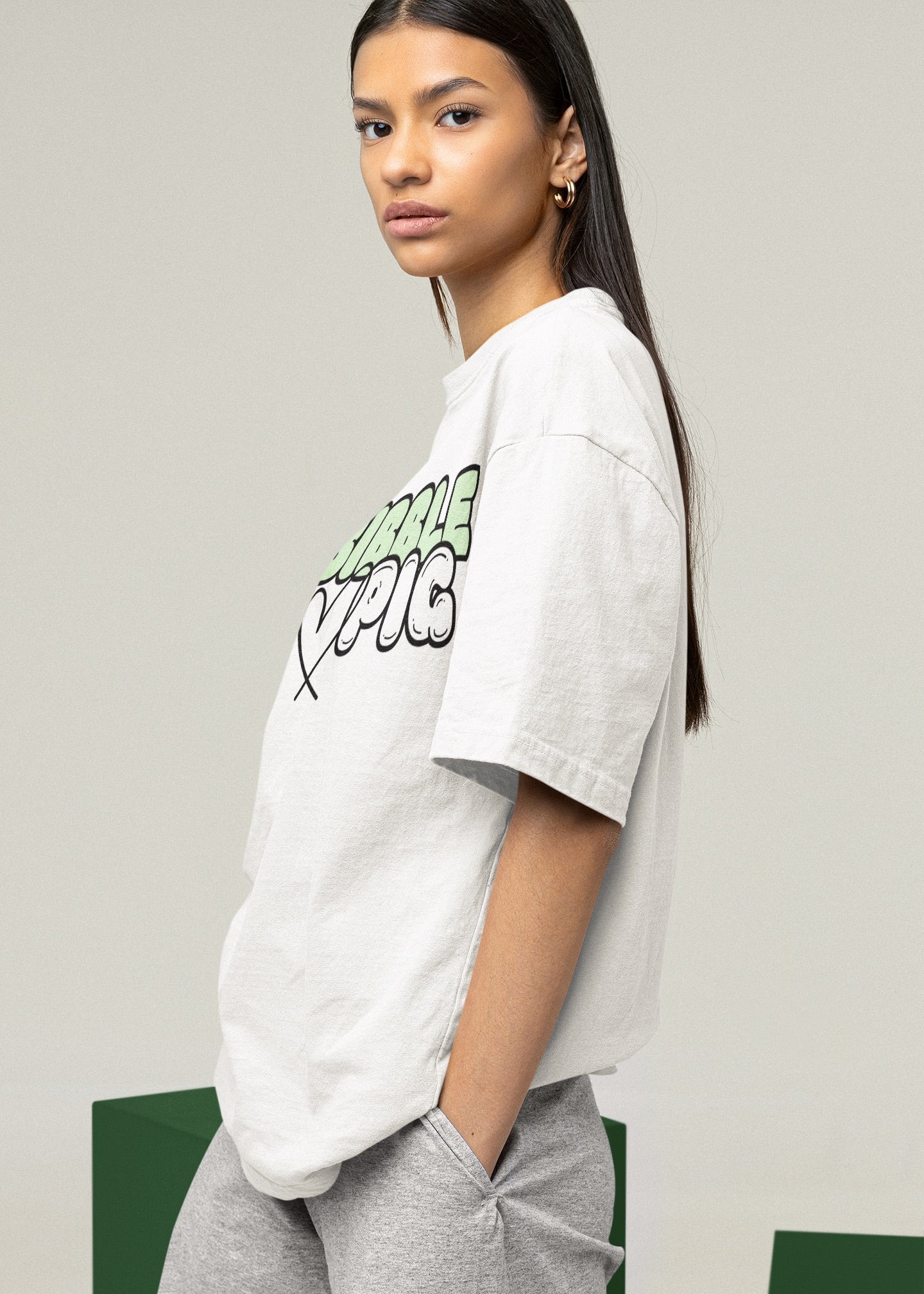 Model wearing Bibble Pig oversized organic cotton t shirt with pastel green logo and black heart design. Unisex UK streetwear fashion.